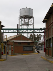 Water tower at industrial site. Red bricks buildings