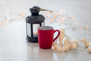 Lantern and red tea cup near light bulb gurland closeup