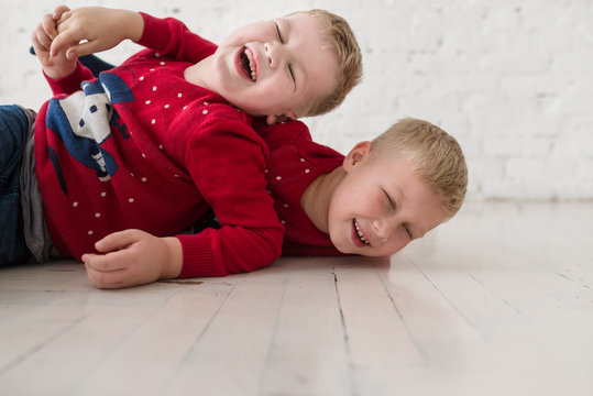 Emotional boys play on the floor at white room in christmas