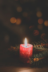 Red burning candle on Christmas tree background