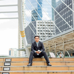 Young Asia handsome businessman drinking hot coffee in the modern city. Breaking and  relaxing business concept