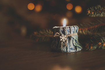 Burning candle in a cozy blue candlestick with a snowflake on the background of a Christmas tree