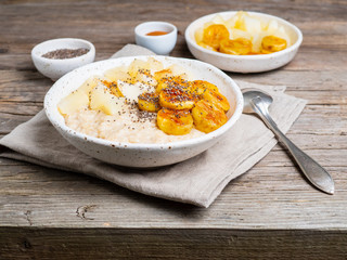 Large bowl of tasty and healthy oatmeal for Breakfast, morning meal. Side view, close up, wooden rustic table