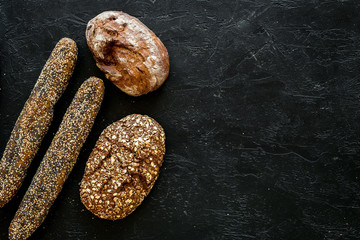 Fitness-bread. Bread made of whole grain flour. Loaf of brown bread and baguette on black background top view copy space