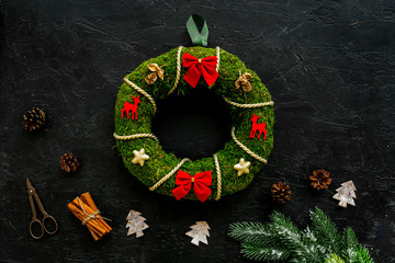 Process of making christmas wreath concept. Green christmas wreath near matherials and instruments, sciccors on black background top view