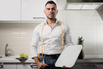 male dietitian holding scales in the kitchen. The concept of a healthy lifestyle
