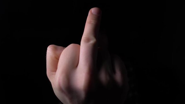 male Hand Showing Middle Finger out of the Darkness. 4K slow motion