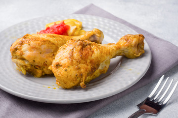 Baked chicken leg Shin with vegetables tomato zucchini on a plate.