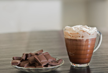 Cup of hot chocolate with pieces of dark chocolate background.