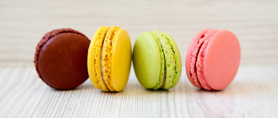 Sweet and colorful macarons on a white wooden background, side view. Close-up.