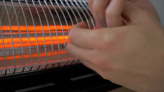 Man warming his hands near the heater. 4K