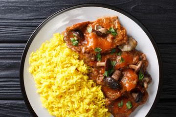 Delicious stewed beef fricando with gravy and wild mushrooms served with yellow rice closeup. Horizontal top view