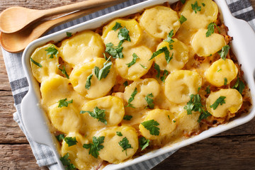 German cuisine: sauerkraut casserole with potatoes, bacon and cheese close-up in a baking dish....