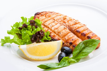 Salmon steak with lemon on a white plate.