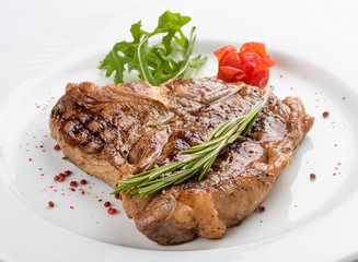 Steak T-bone with greens. On a white plate.