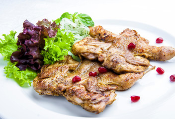 Baked quails with greens on a white plate