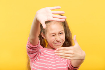 girl pretending to take a picture through her hands creating a virtual photo frame. arts hobby and...