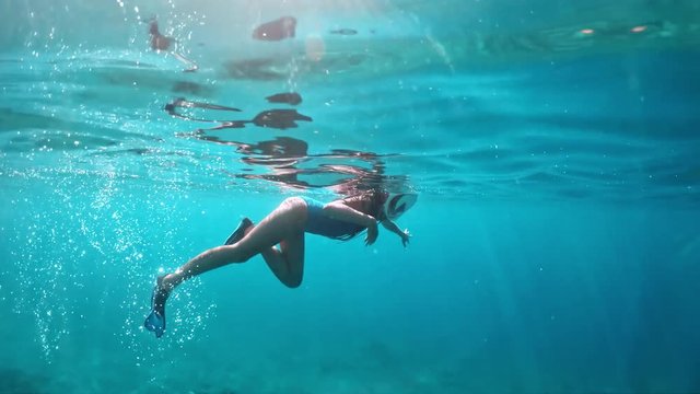 Young lady snorkeling over coral reefs in a tropical sea. Woman with mask snorkeling in clear water.