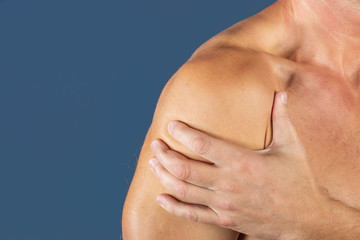 Man holding his sore shoulder trying to relieve pain. Health problems