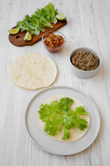 Making shrimp tacos on white wooden background, high angle view. Mexican kitchen.