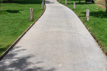 concrete walkway or pathway on green grass lawn in resort park with warm sunlight
