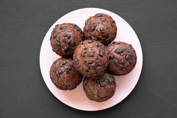 Chocolate cupcakes on pink plate on black surface, top view. Flat lay, overhead, from above.