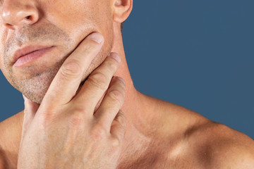 Naklejka premium Sad depressed man in pain holding his cheek. Portrait of a man on blue background. emotion facial expression. feelings and people reaction. Toothache
