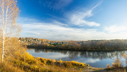 Beautiful panorama of morning on the calm river with village on their bank 