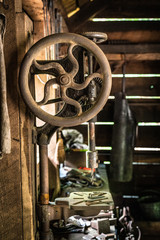 Vintage old wooden barn with antique blacksmith tools. Closeup of rusty table drill.