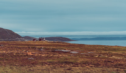 Peaceful landscape in Norway, lonely house at lake, hills in the background, cloudy afternoon.