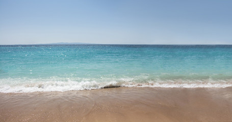 Fototapeta na wymiar Seashore with wet sand and turquoise waters.