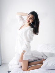 Happy Asian woman relaxing on bed, lifestyle concept.