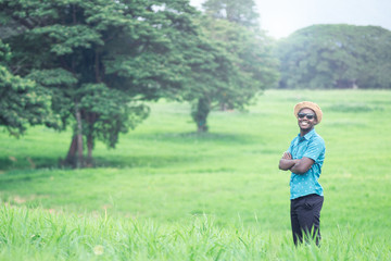 Naklejka na ściany i meble African man travelers stand and smile happily among green meadows.