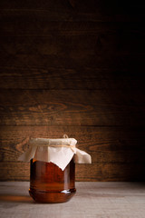 Honey in cans as well as honeycomb sots a wooden spoon on a wooden background