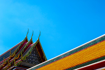 Fototapeta na wymiar Temple roof in Thai temple in Thailand under bright blue sky 