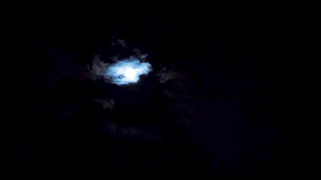 Time lapse - clouds passing by moon at night. Full moon at night with clouds. Beautiful nightly spooky background.