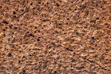 Rough sand stone texture. Porous orange stone closeup. Weathered grungy surface photo background.