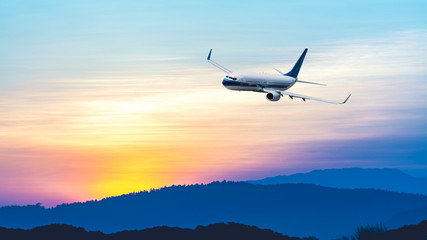 Fototapeta na wymiar Airplane flying at sunset sky
