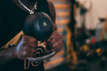 Black young muscular man training with kettlebell at gym. Strength and motivation