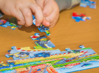 Baby hands assemble the puzzle on the table