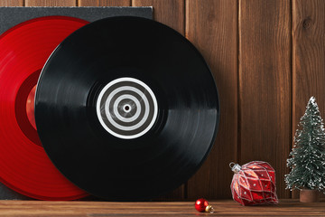 Christmas greeting card frame for your text design. Bright red and black vinyl records for a turntable on a gray cover and a red glass vintage ball, a Christmas tree on an old wooden plank. Front