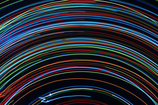 Blurred bright luminous multicolored stripes in the form of an arc from diode bulbs LED from Christmas lights screen closeup. Bright abstract background ideal for any design
