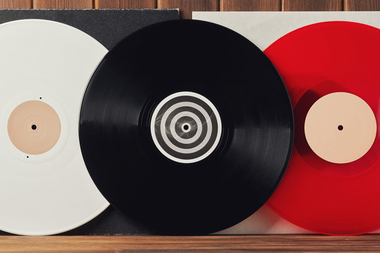 Bright white, red and black vinyl record for a turntable on a gray and white covers on an old wooden plank background. Greeting card frame with place for your text design. Front view close up