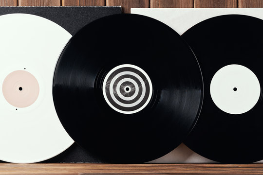 Bright white and black vinyl record for a turntable on a gray and white covers on an old wooden plank background. Greeting card frame with place for your text design. Front view close up