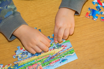 Obraz premium Baby hands assemble the puzzle on the table