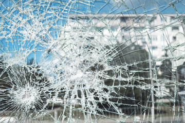 Criminal incident at the bus stop. Shooting a pistol. Hole and cracks in the glass of a city bus stop. Cracked glass texture against the blue sky. Cracked glass with a hole from a bullet. Vandalism