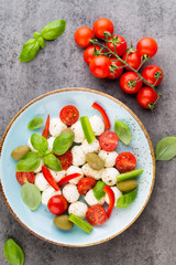 Delicious caprese salad with ripe cherry tomatoes and mini mozzarella cheese balls with fresh basil leaves.