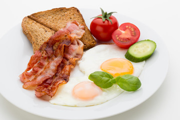 Fried eggs with bacon on the wooden table.