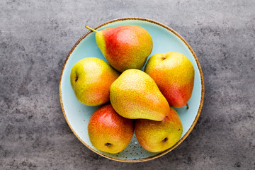 Fresh bio pear with leaves on the plate. Gray stone table.