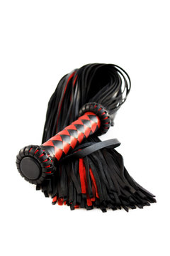 Red-black floger with a patterned handle and leather tails. vertical photo on white background.concept of pleasure from pain